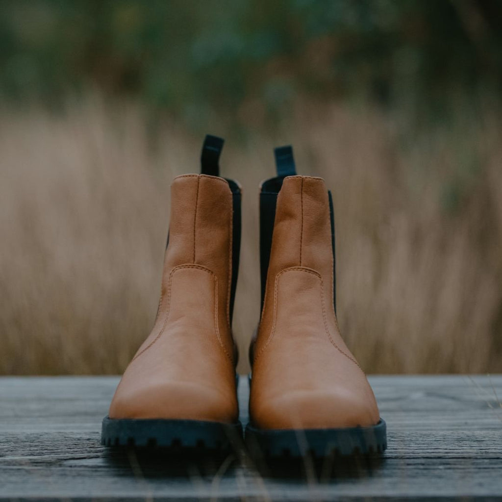 4. KIRA 3.0 Chelsea Boots in brown, shown on wooden surface with natural background