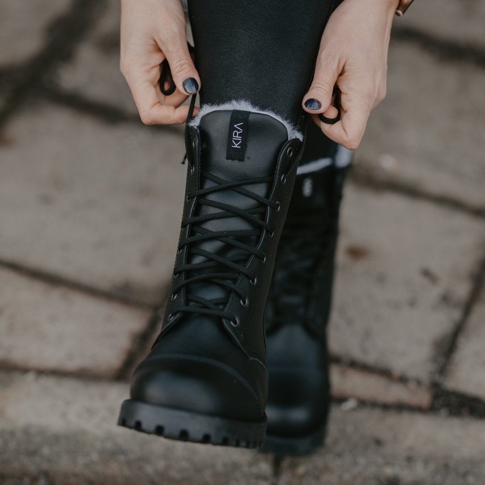 7. Woman adjusting KIRA 4.0 black boots with side zipper and vegan wool lining, shown outdoors