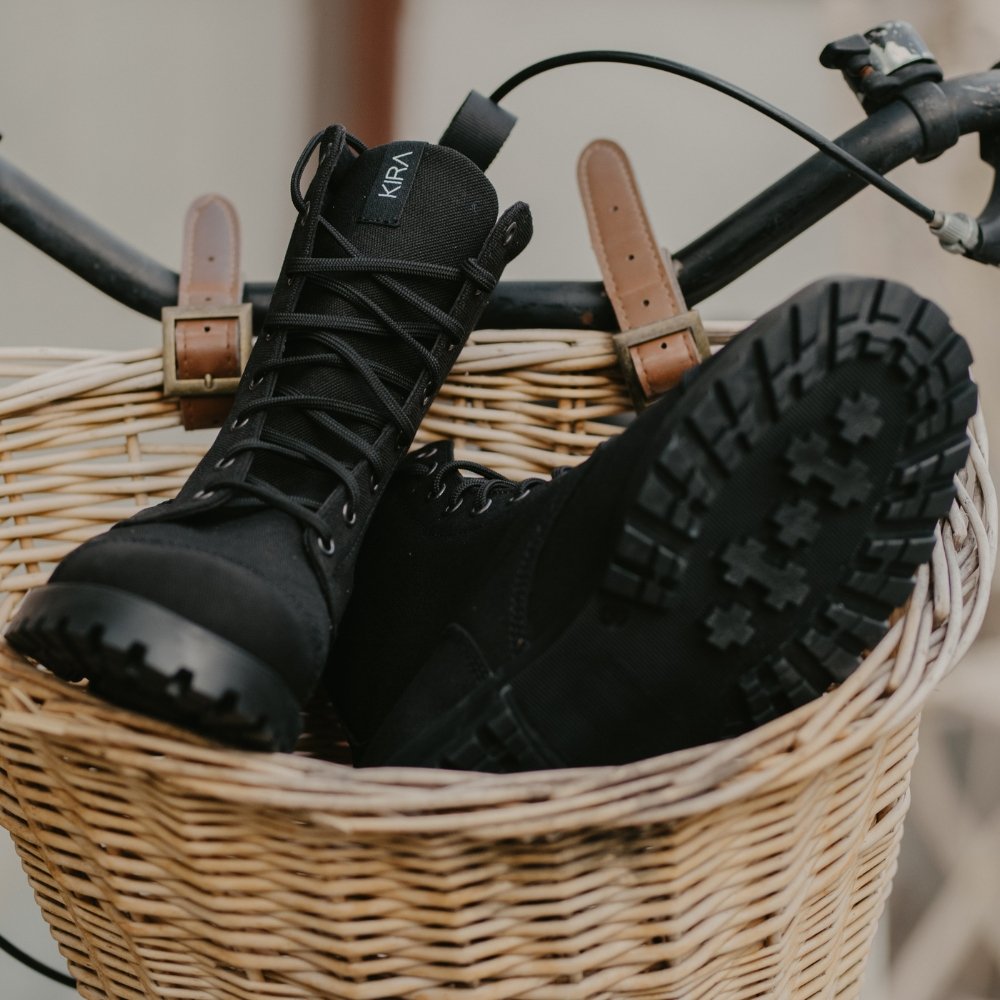 2. KIRA 5.0 black boots in a bicycle basket, highlighting deep-patterned rubber outsole