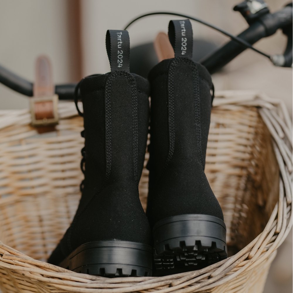 3. Back view of KIRA 5.0 black boots in a bicycle basket, showing recycled textile and heel reinforcement