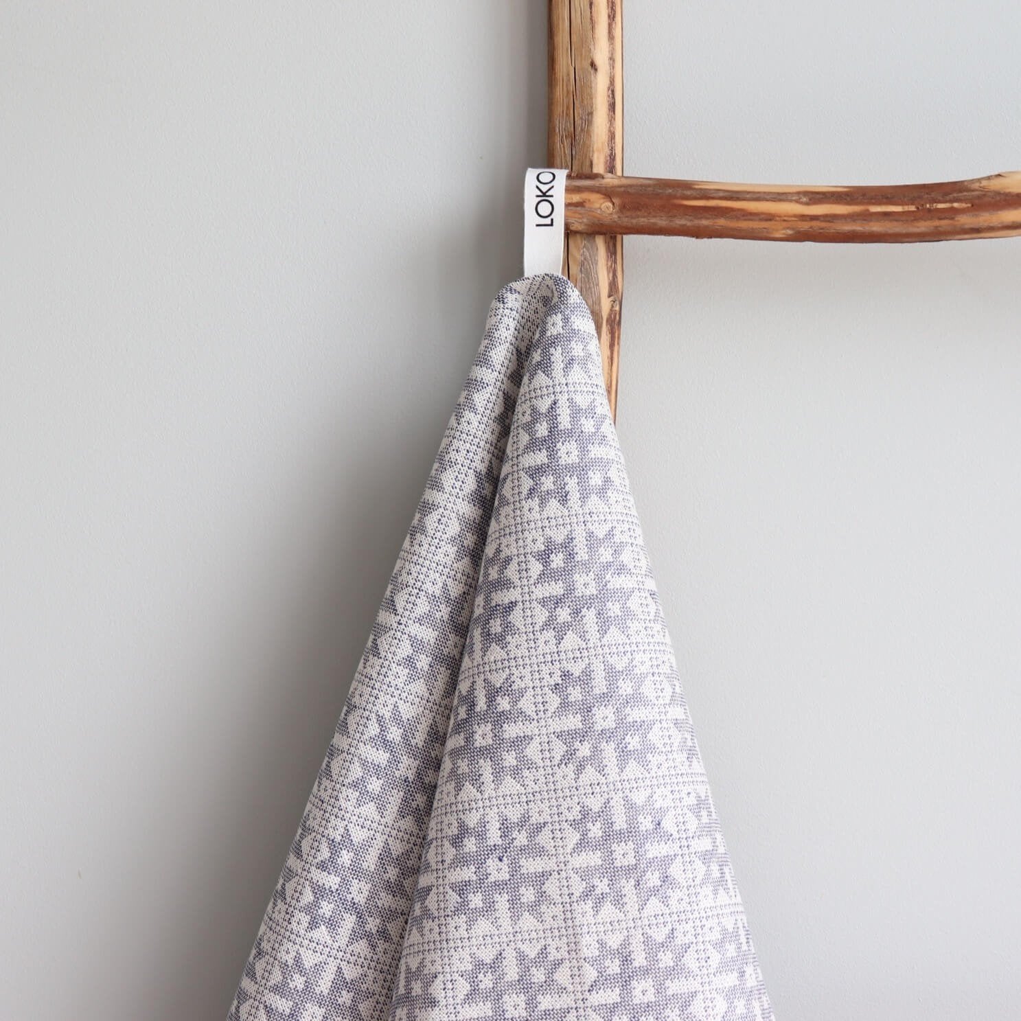 2. Kitchen towel with Pärnumaa pattern hanging on wooden ladder, featuring LOKO brand tag and grey design