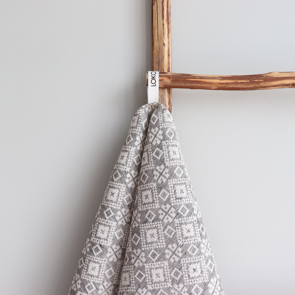 2. Close-up of grey kitchen towel with Kodavere folk art pattern and LOKO brand tag on wooden ladder