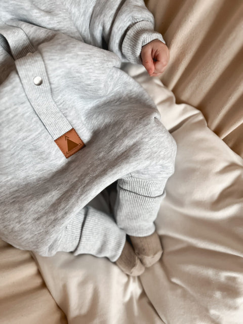 3. Close-up of Zezuzulla melange grey jumpsuit showing ribbed cuffs and leather logo patch