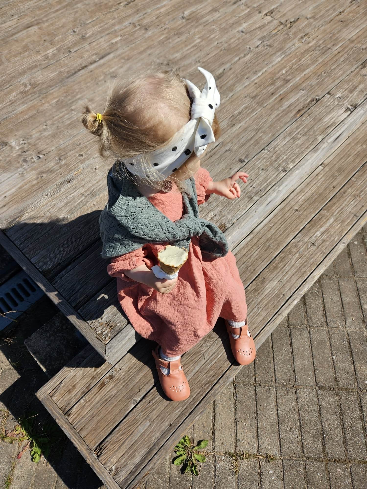 1. Child wearing Omaking Mutsu coral slippers outdoors, sitting on wooden steps