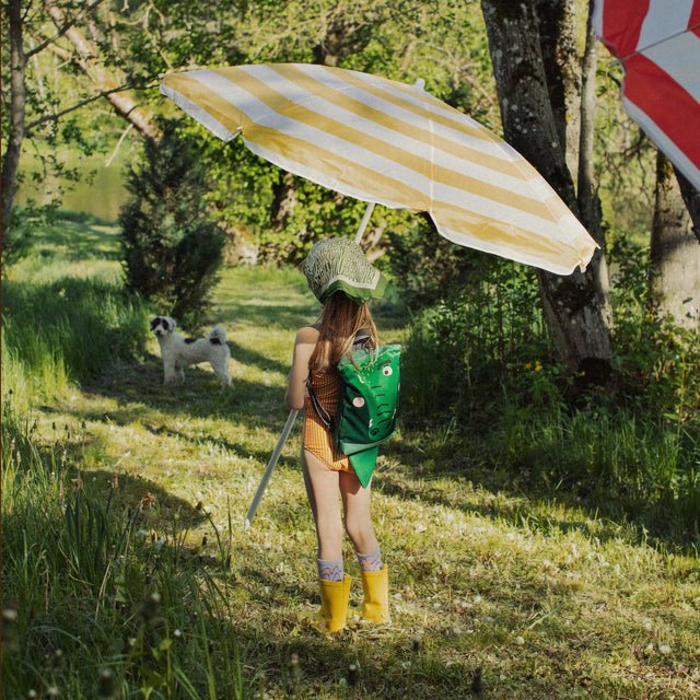 3. Girl with Muni crocodile backpack walking in park with umbrella