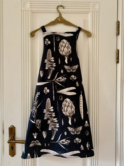 2. Hortensias Home Seeds Carbon apron with botanical print hanging on a white door