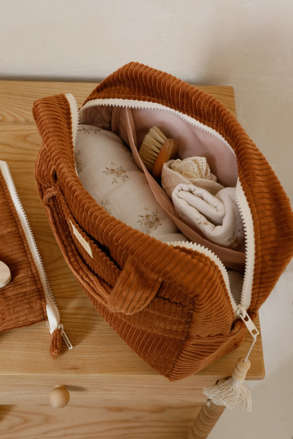 6. Open caramel makeup bag on a dresser, filled with toiletries and fabric, showcasing its spacious interior