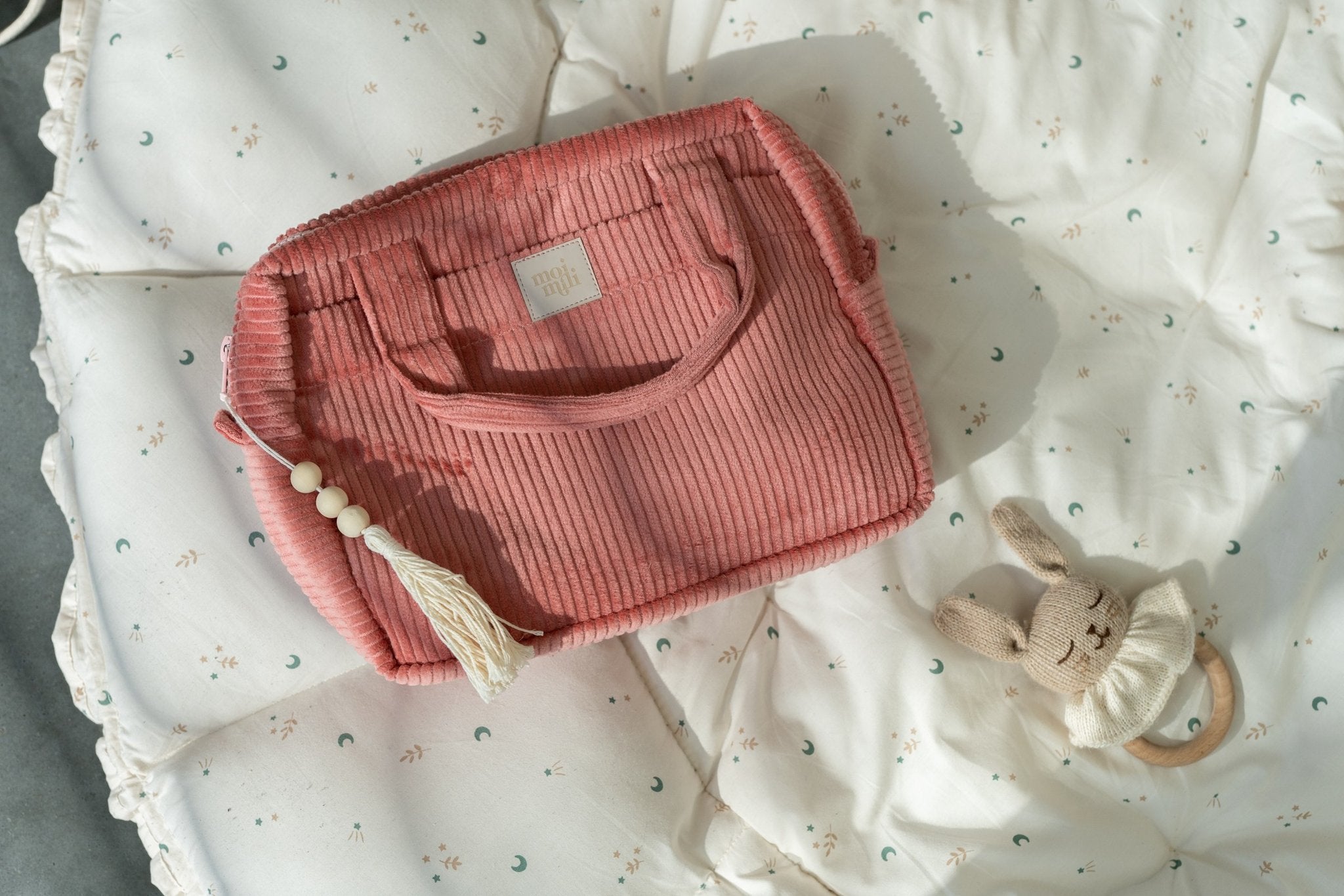 5. Coral makeup bag with tassel on quilted fabric, accompanied by plush toy