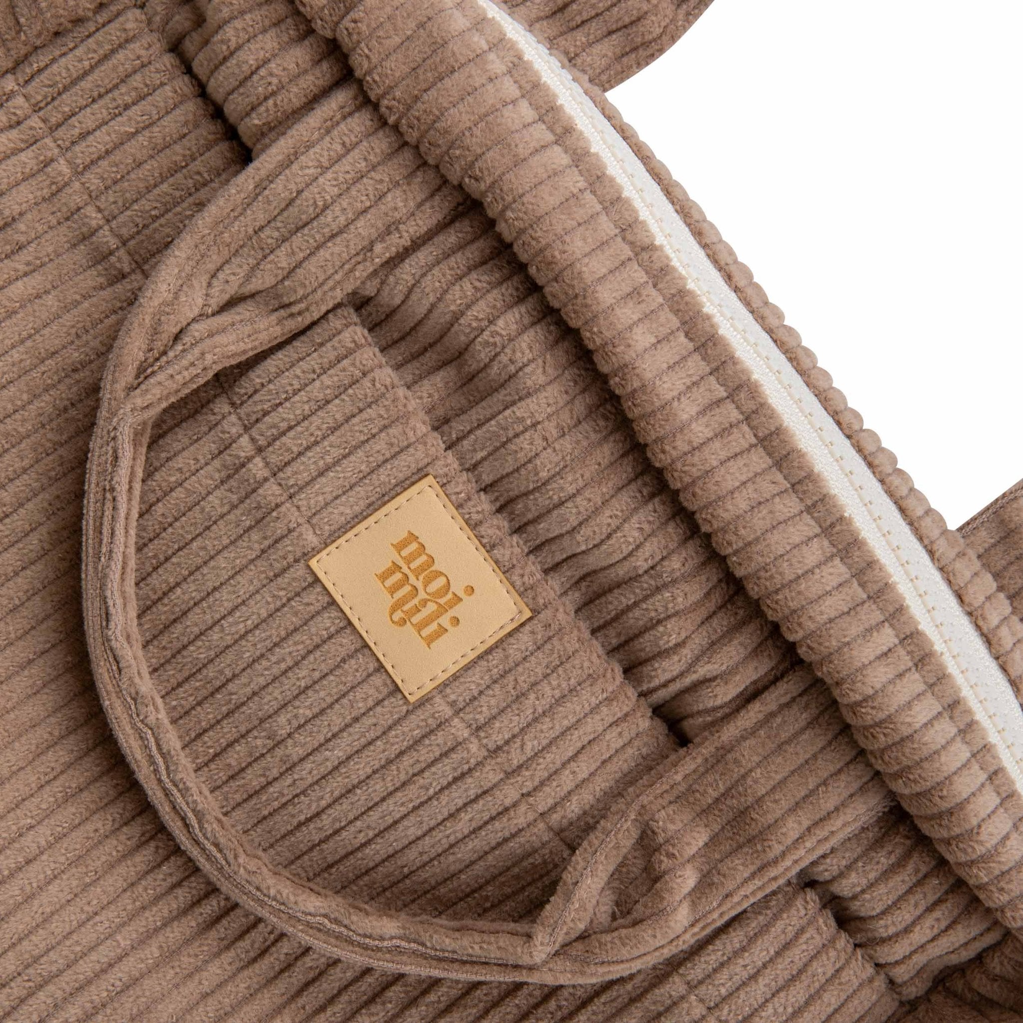 4. Close-up of Moi Mili logo on latte-colored ribbed fabric of large makeup bag, highlighting texture and brand detail.