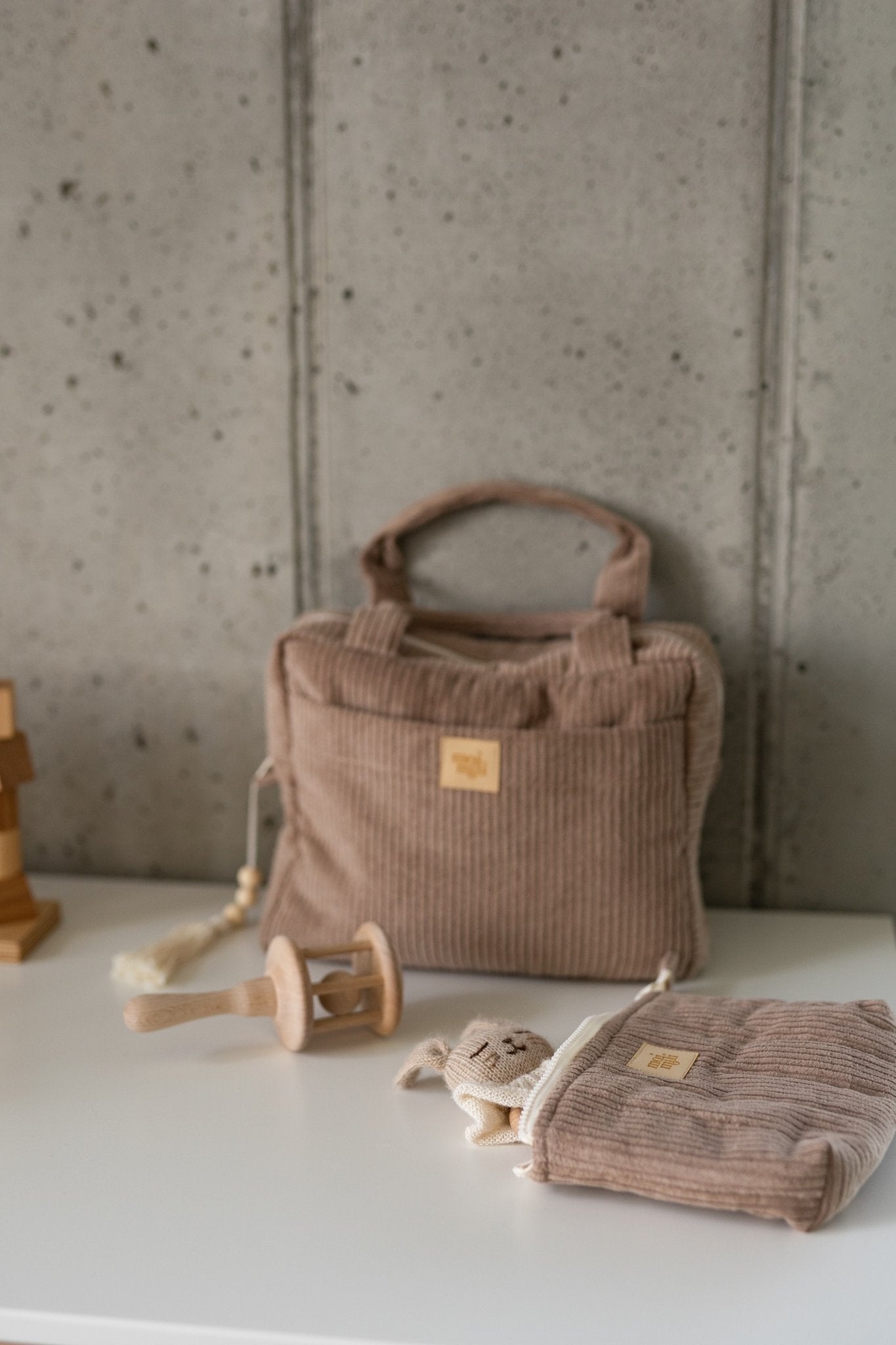 6. Latte-colored large makeup bag with Moi Mili logo on a white surface, next to toys, highlighting versatility and use for storage.