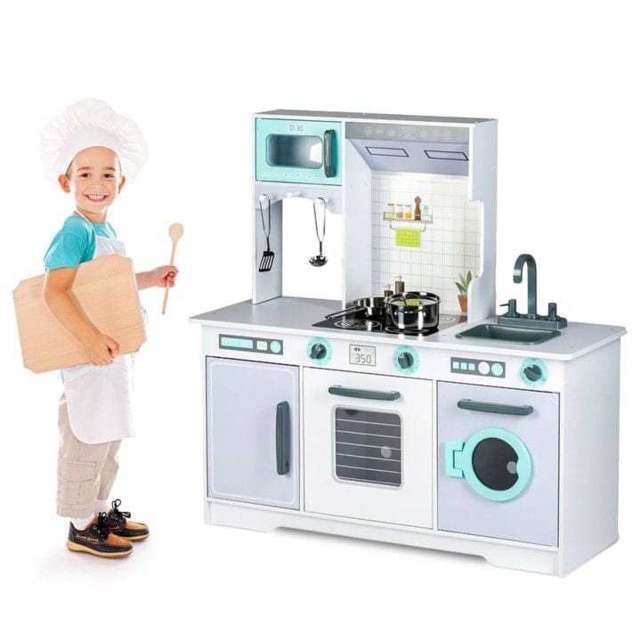 1. Child dressed as a chef standing next to Angelove large wooden play kitchen with accessories, featuring oven, microwave, and sink in a bright room