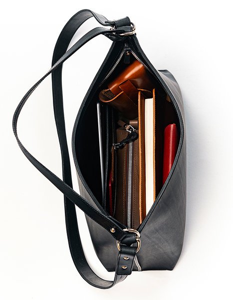 2. Top view of Stella Soomlais black leather handbag filled with books and essentials, highlighting spacious interior and zipper closure.