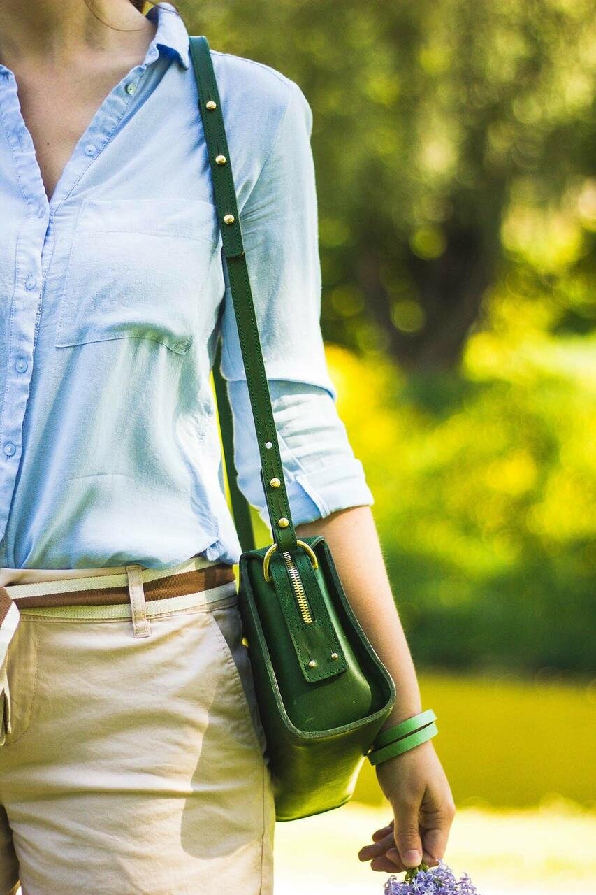 8. Woman wearing green Stella Soomlais handbag with adjustable strap, outdoors in sunny setting