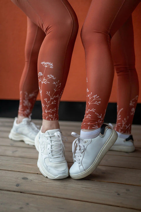 2. Close-up of women's legs in Peachlabel 'Wildflowers' brown leggings, highlighting floral design near ankles