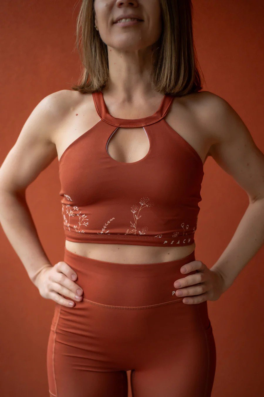 1. Woman wearing Peachlabel Wildflowers brown sports bra and leggings set, showcasing floral design in lifestyle setting
