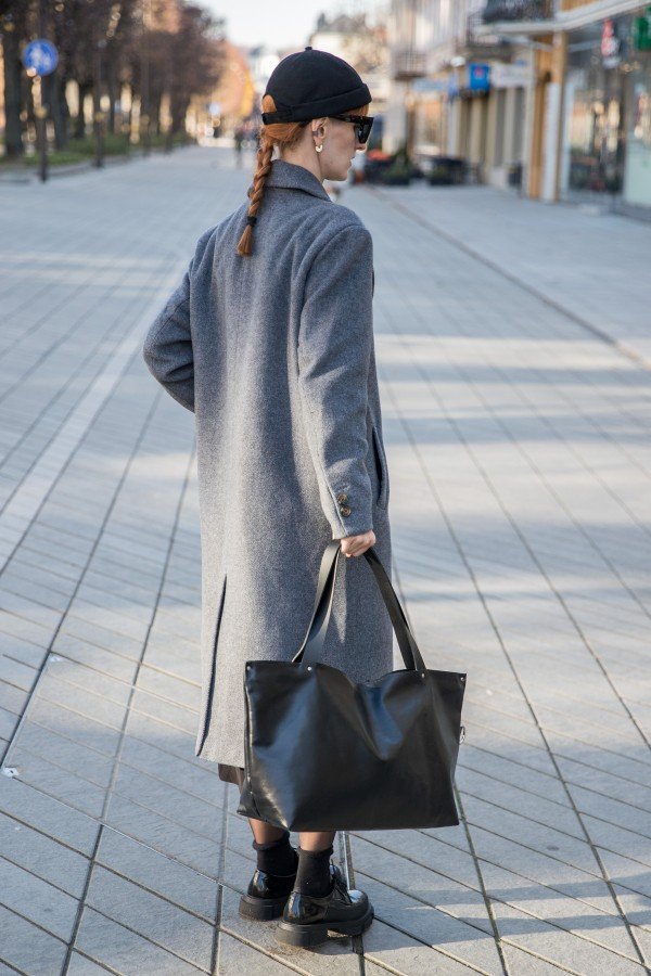1. Woman walking on street holding PYKOK Large Handbag Lima in soft black leather, showcasing spacious design