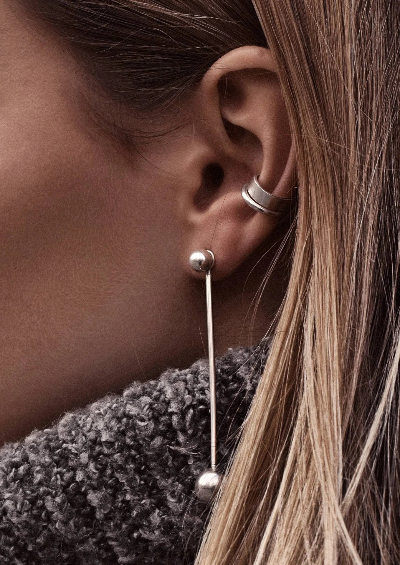 3. Women's silver Line Ear Cuff by NO MORE styled with long drop earrings and a grey sweater
