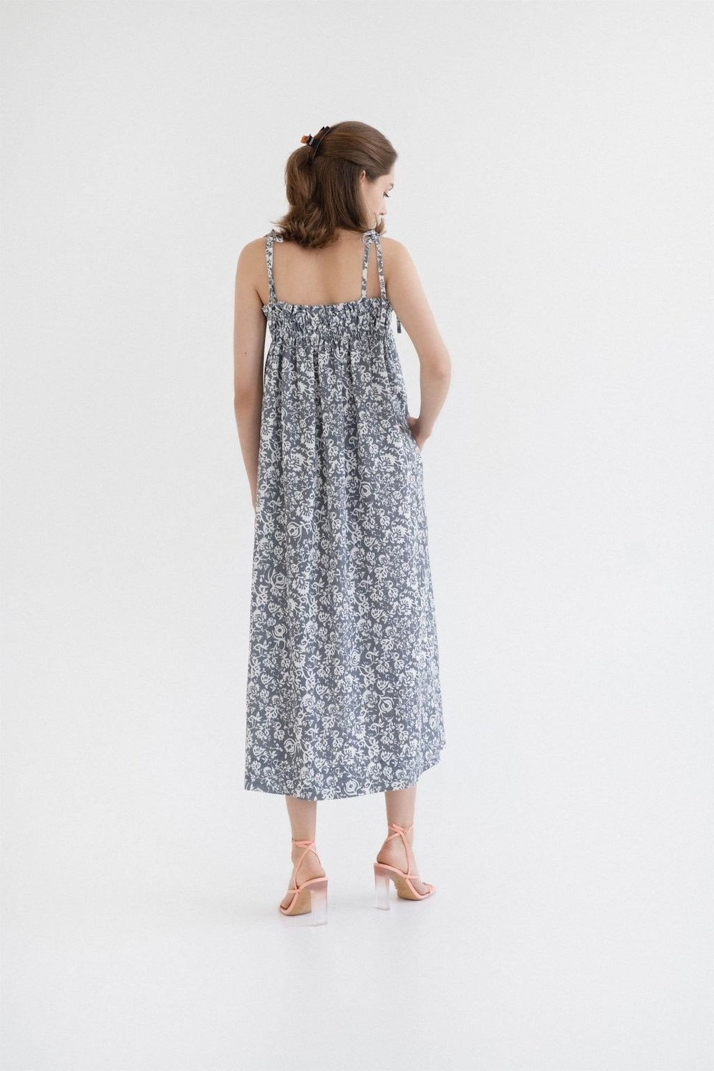 2. Back view of woman wearing Linen Tales Ballade dress in porcelain flowers print with tie spaghetti straps in a studio setting