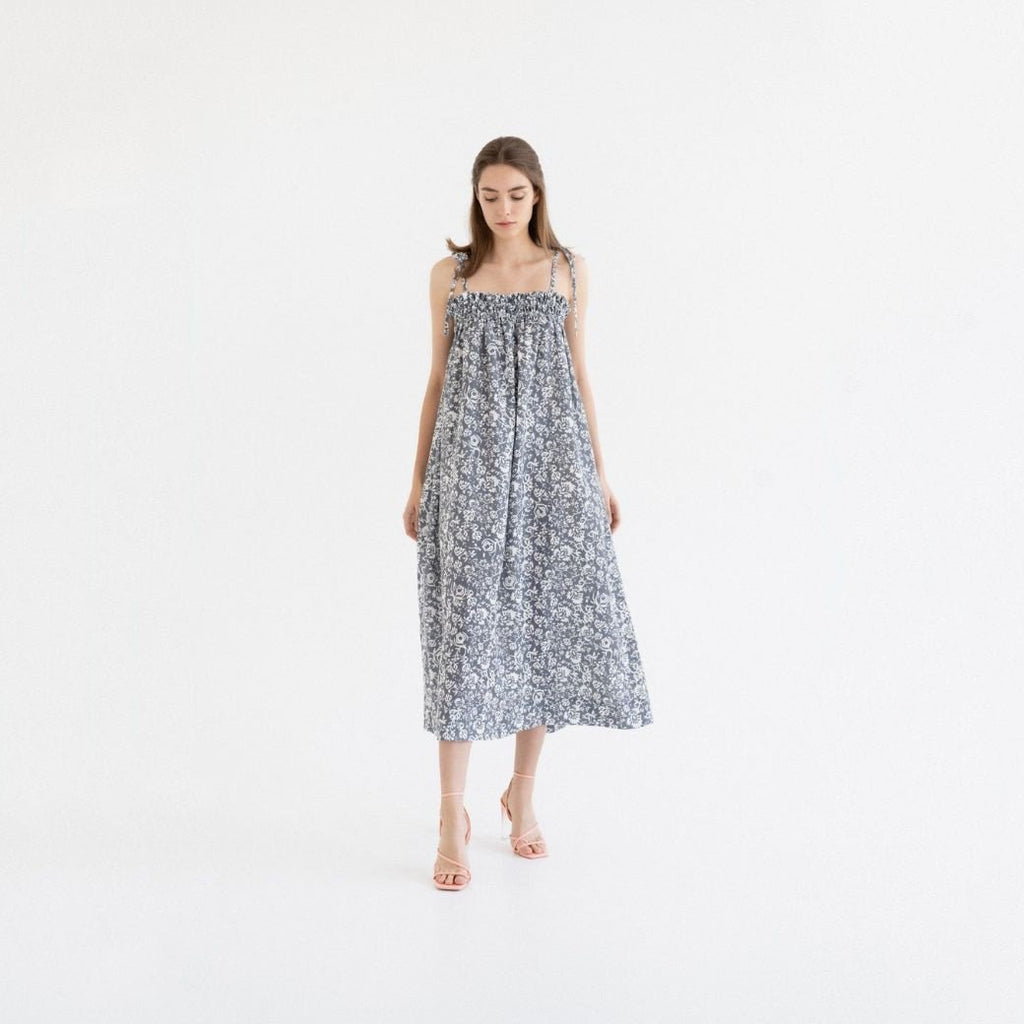 1. Woman wearing Linen Tales Ballade dress in porcelain flowers print with tie spaghetti straps, standing in a bright studio setting