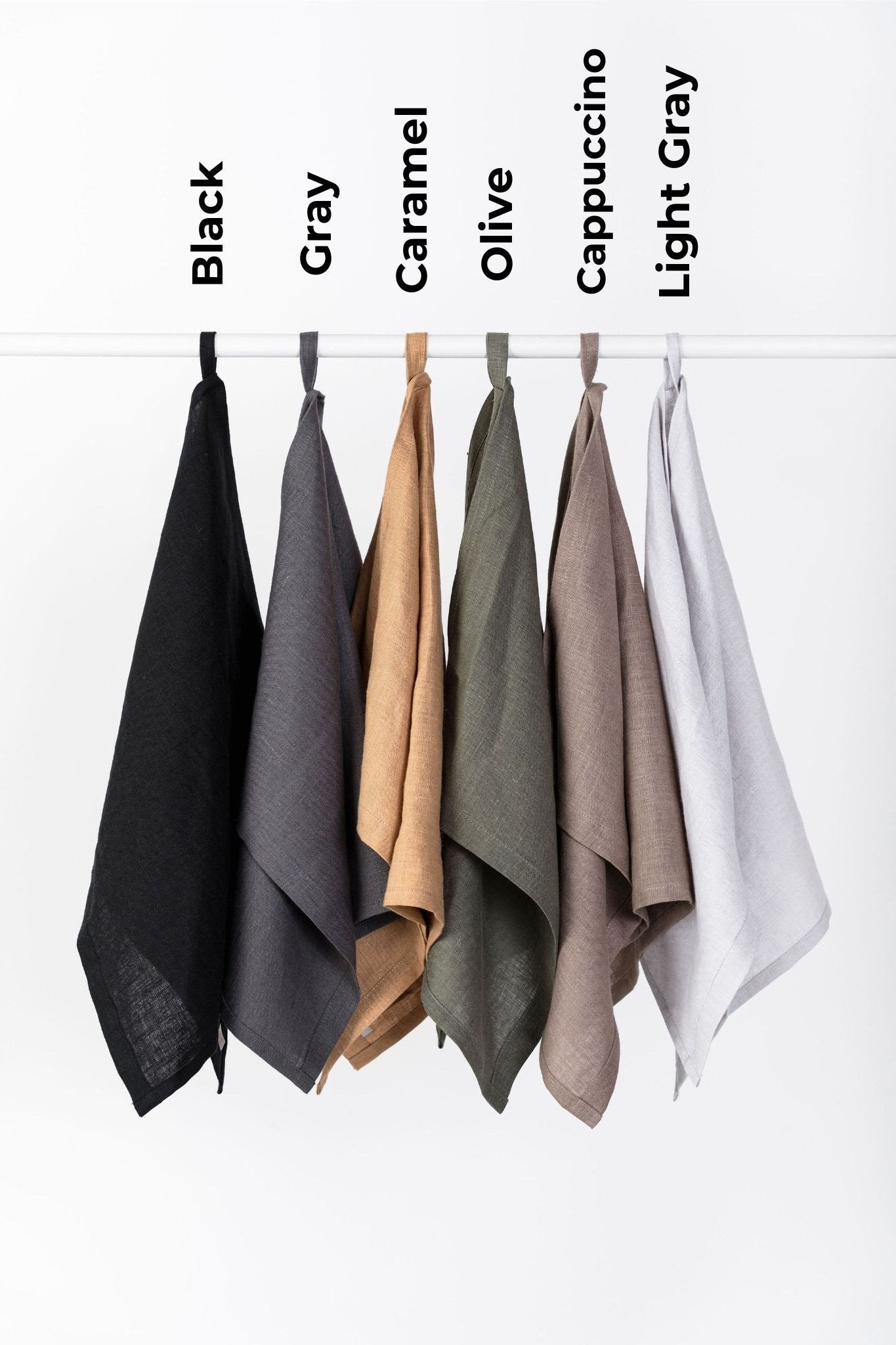 2. Six linen kitchen towels labeled with colors black, gray, caramel, olive, cappuccino, and light gray hanging on a rod