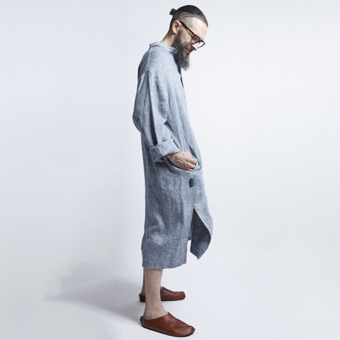 3. Side view of man in blue-gray linen dress with hands in pockets and brown shoes