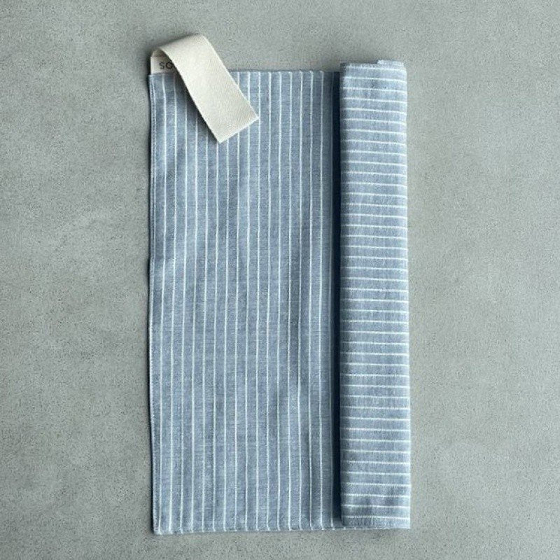 8. Linen sauna seat cover partially rolled, showing light striped pattern and cotton hook on grey background.