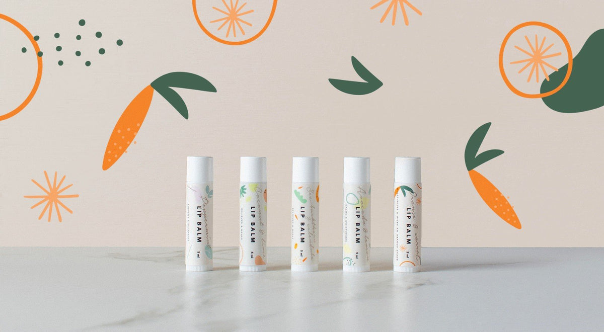 1. Five BONOBO lip balm tubes with orange and carrot illustrations on marble surface against decorative background