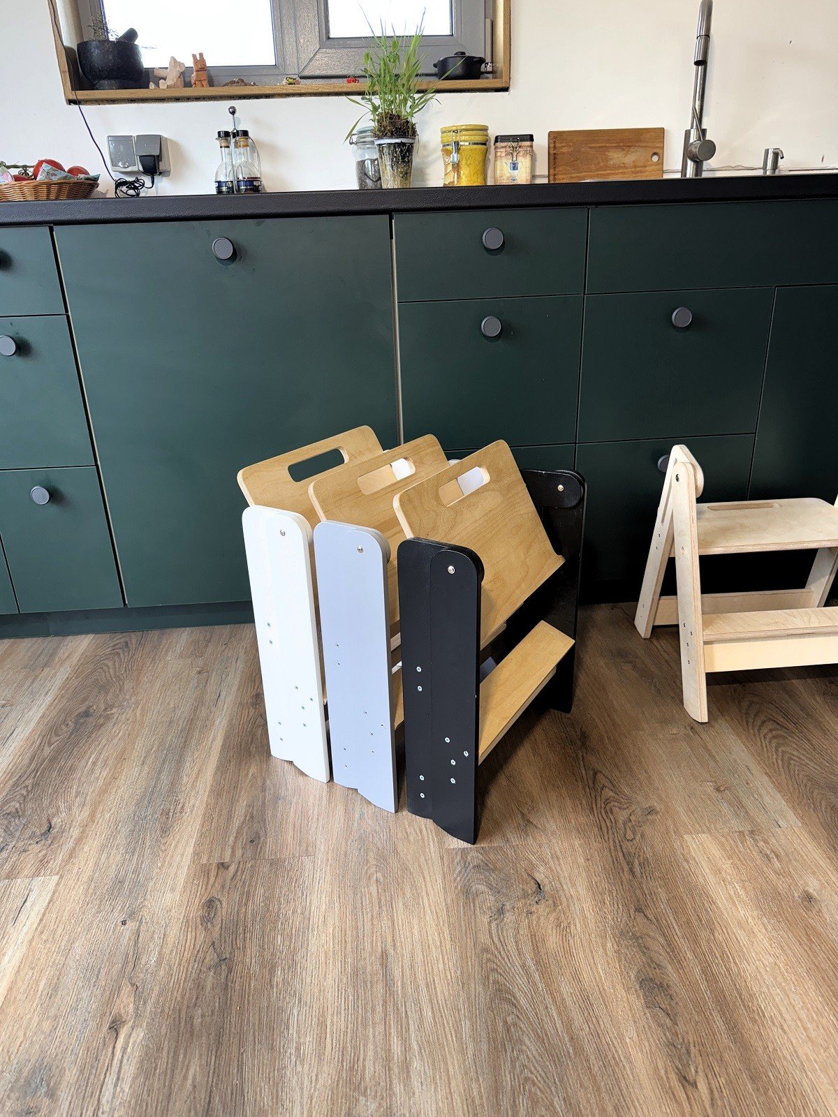 1. Folded wooden step stools in various colors beside a kitchen cabinet