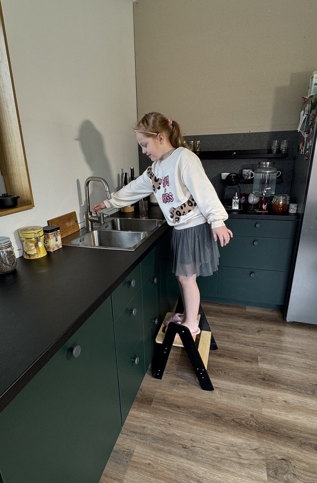 1. Girl using wooden step stool to reach kitchen sink