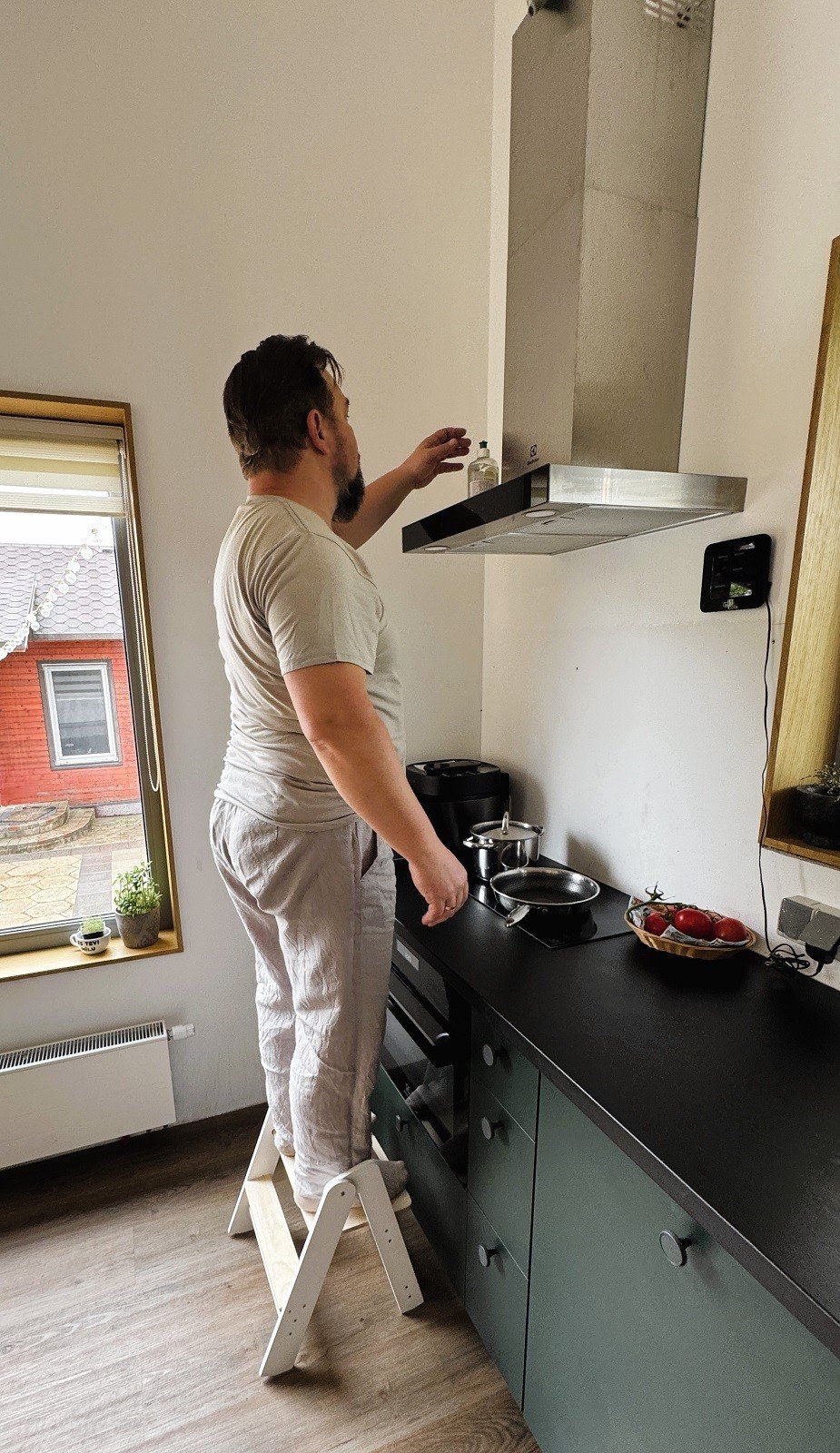 1. Man using wooden step stool to reach kitchen range hood