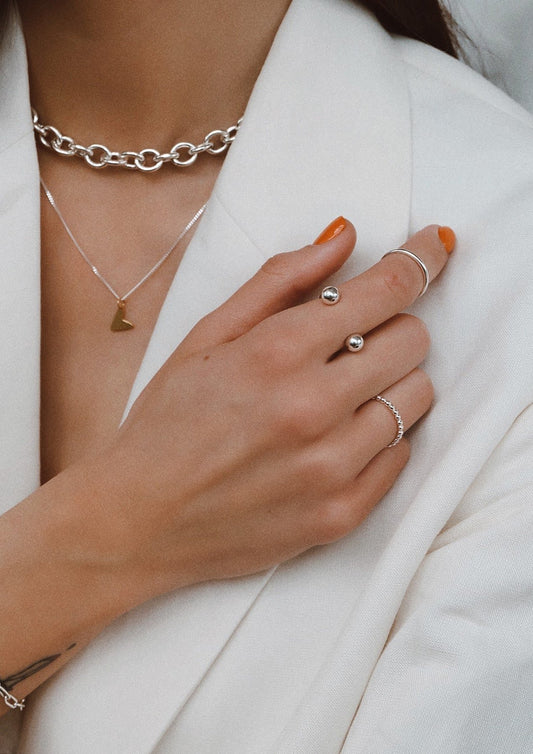 1. Women's Love Necklace in gold by NO MORE, styled with silver rings and a white blazer
