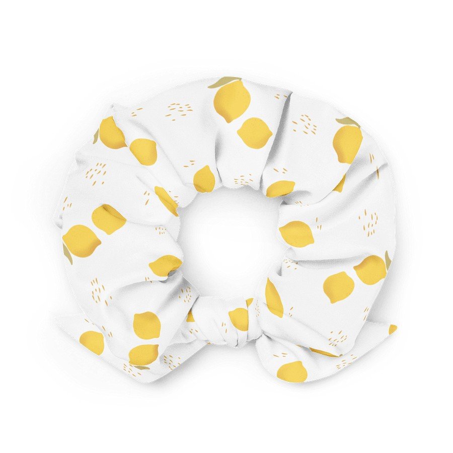1. White scrunchie with yellow lemon print made from recycled polyester, shown in a flat lay highlighting the smooth fabric and elastic fit