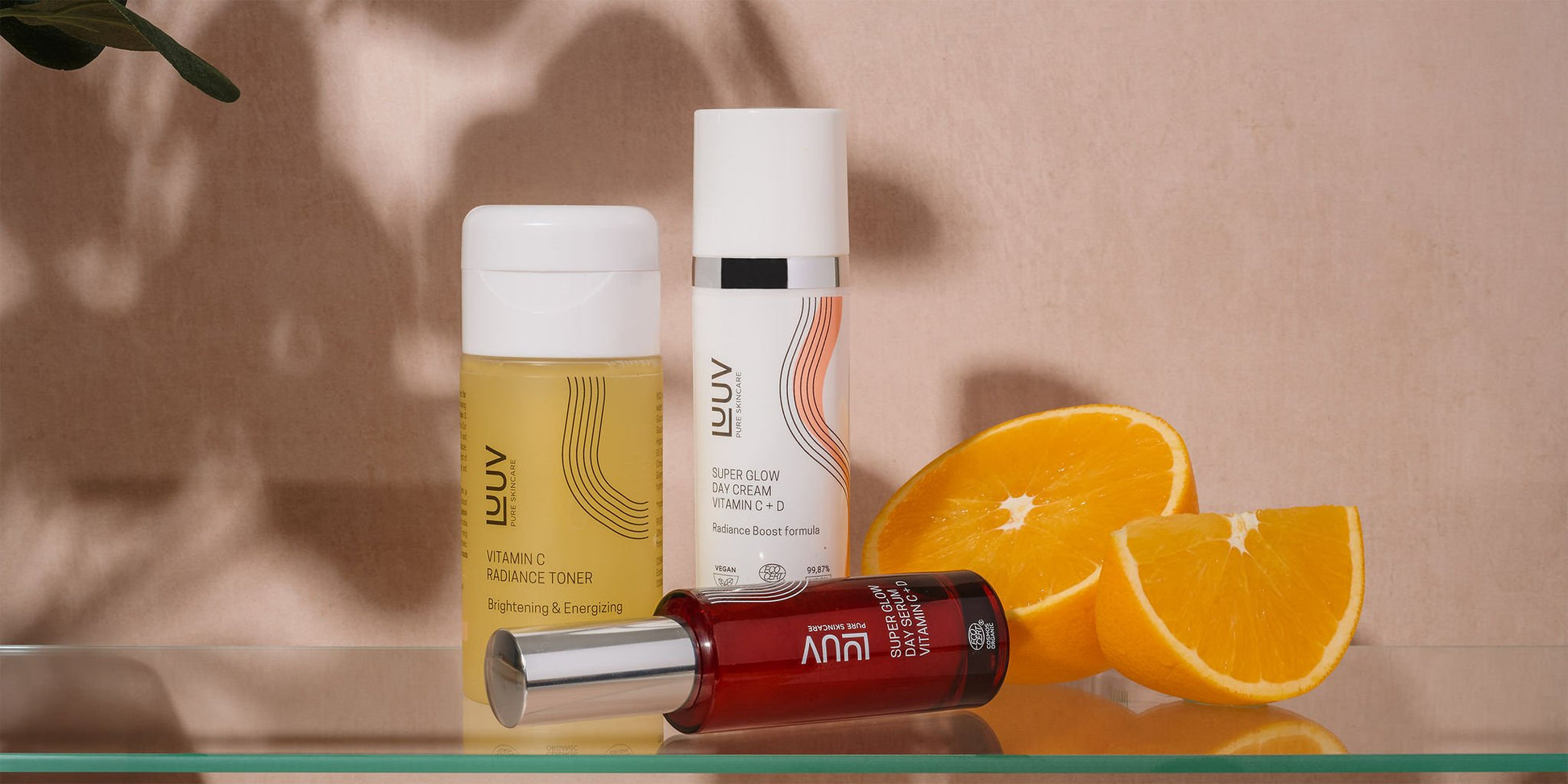 2. LUUV skincare set featuring Vitamin C Radiance Toner, Day & Glow Serum, and orange slices on a glass shelf