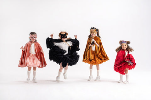 3. Four children in colorful capes jumping in a studio setting