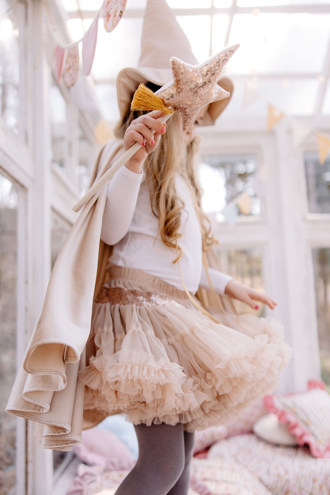 4. Girl in cream cape holding star wand in bright room