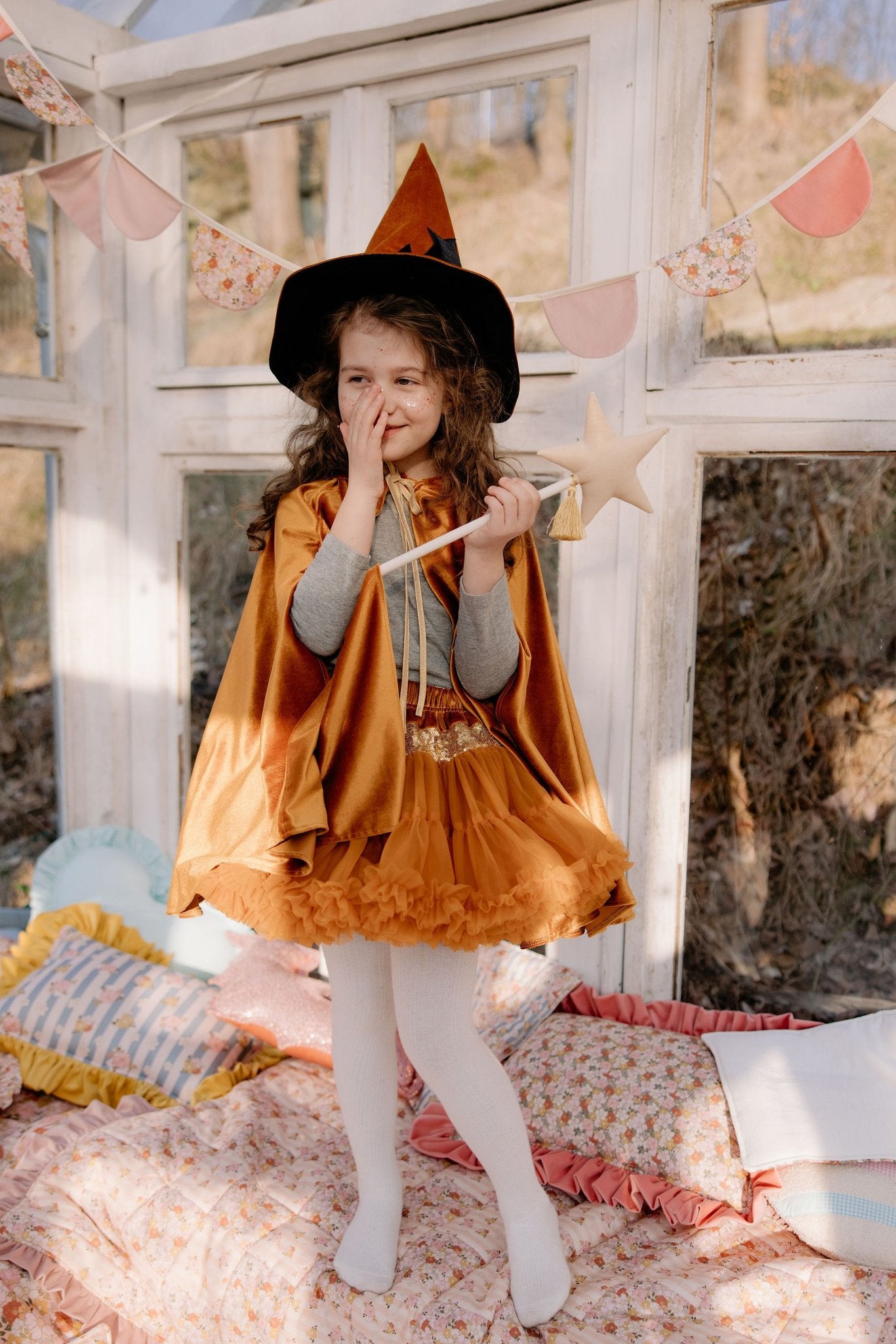 14. Child in golden cape holding wand in sunlit room