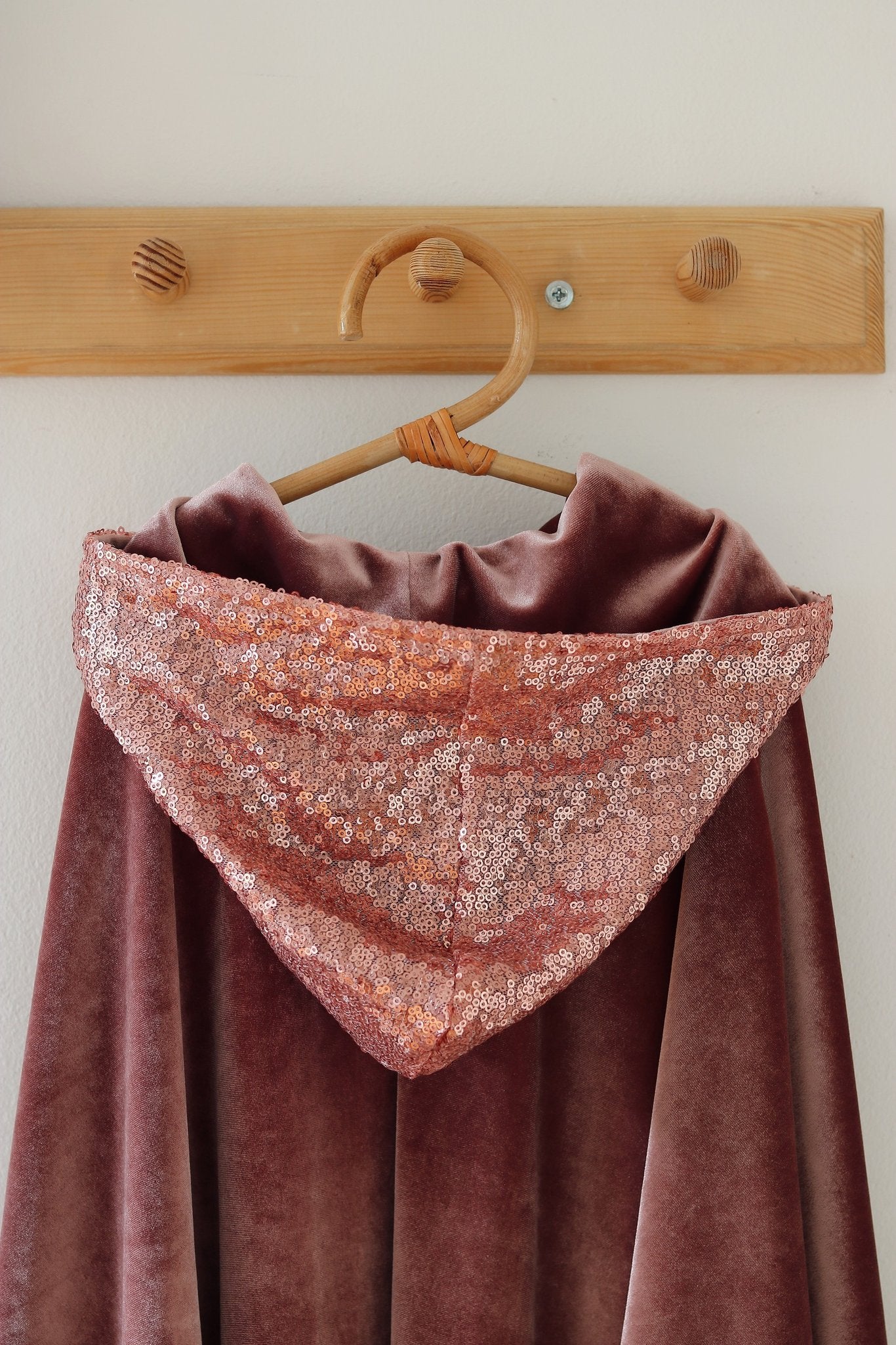 10. Close-up of pink velour hood with sequined trim on wooden hook