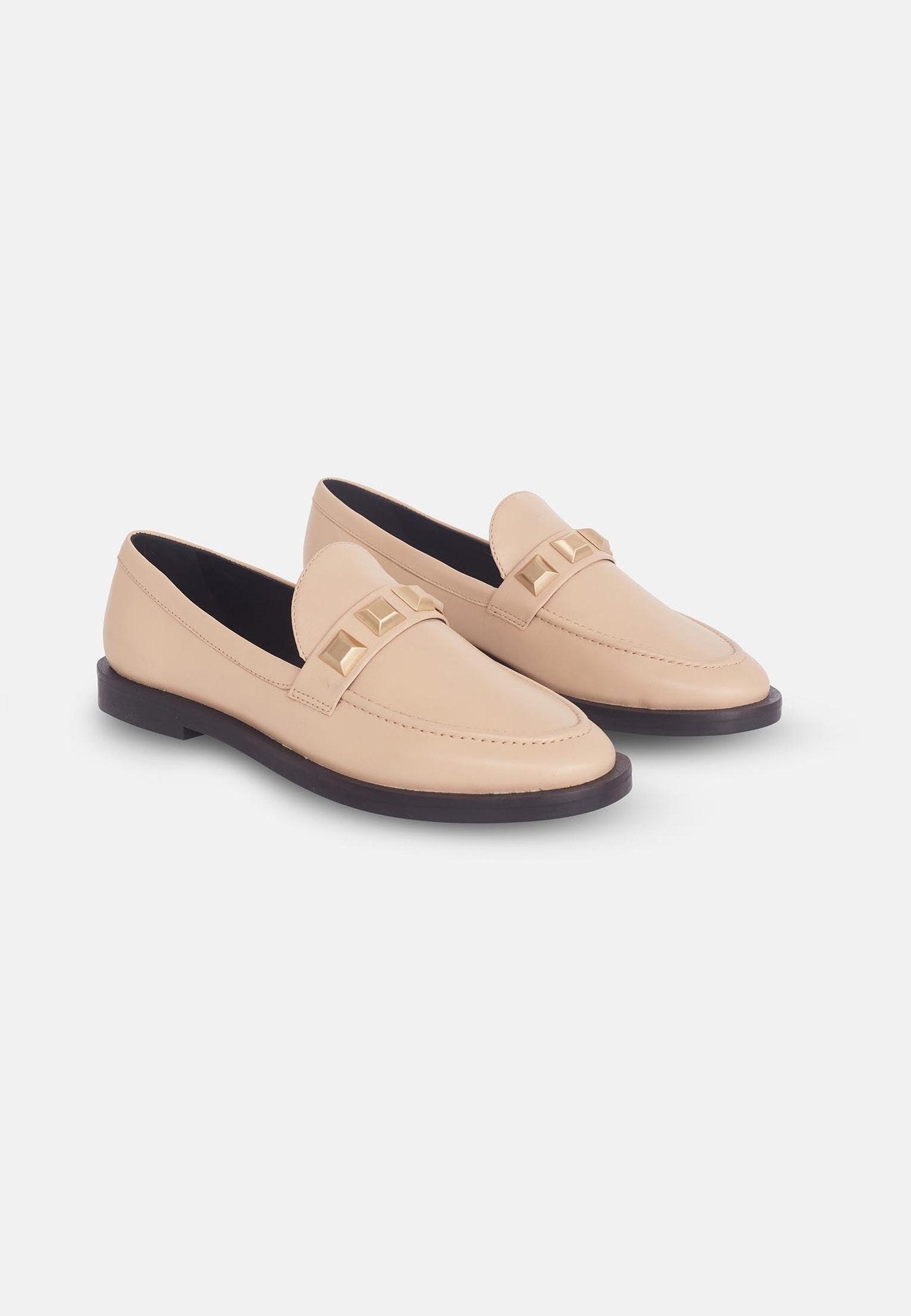 8. Side view of beige Mangará Caete leather loafers with metal studs, studio setting