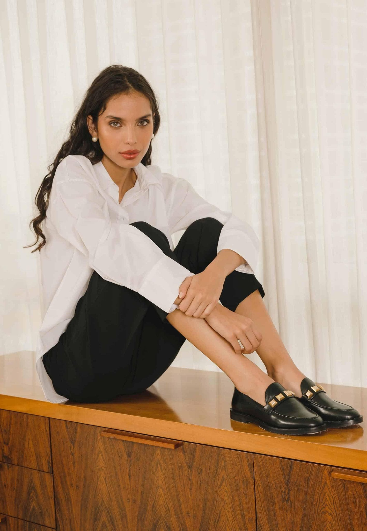 9. Side view of black Mangará Caete leather loafers with metal studs, studio setting