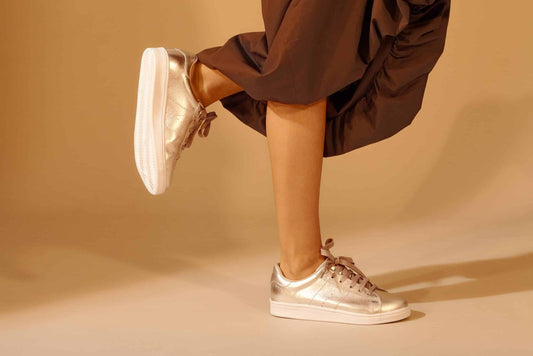 1. Women's metallic golden leather sneakers by Mangará, worn by a model in a stylish setting