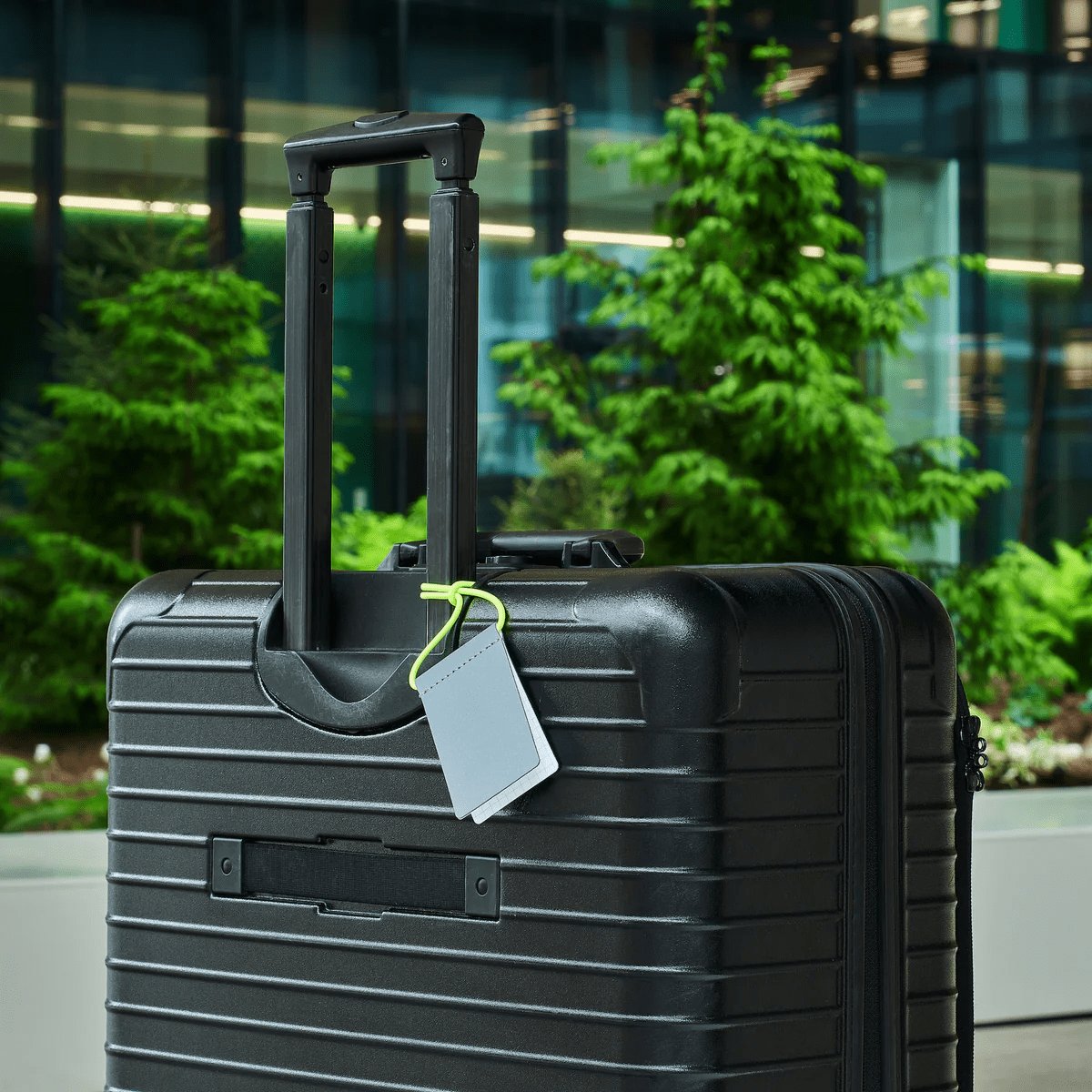 8. Grey MARCH Reflective Luggage Tag with neon yellow strap on suitcase, shown in outdoor setting