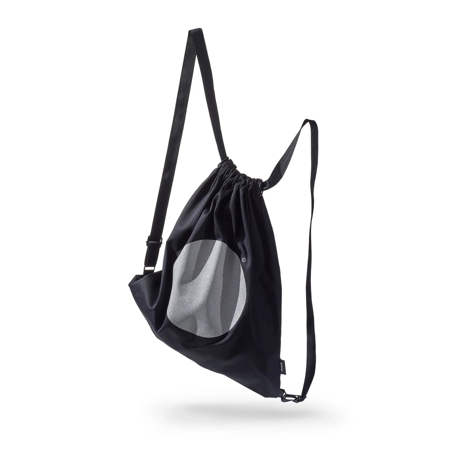 4. Side view of March Design Studio's Water Resistant Reflective Backpack DOT in studio, showing reflective circle and water-resistant material