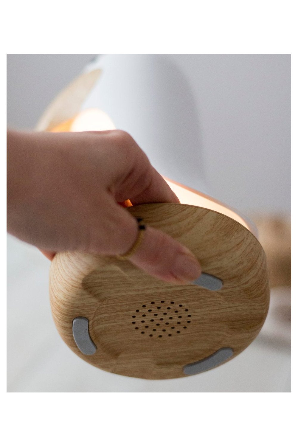 3. Close-up of hand holding the base of pink bird lamp showing speaker grill