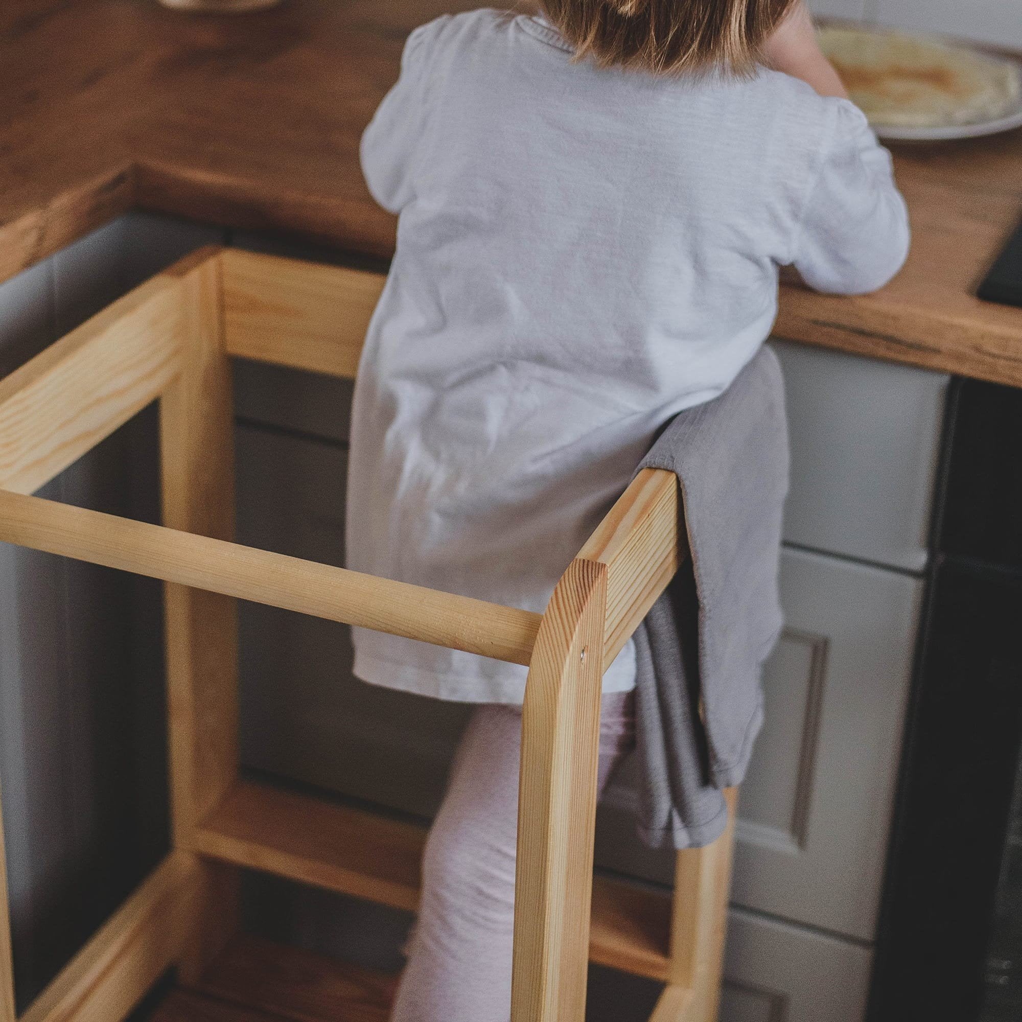 8. Back view of child on MeowBaby kitchen helper, interacting with kitchen counter
