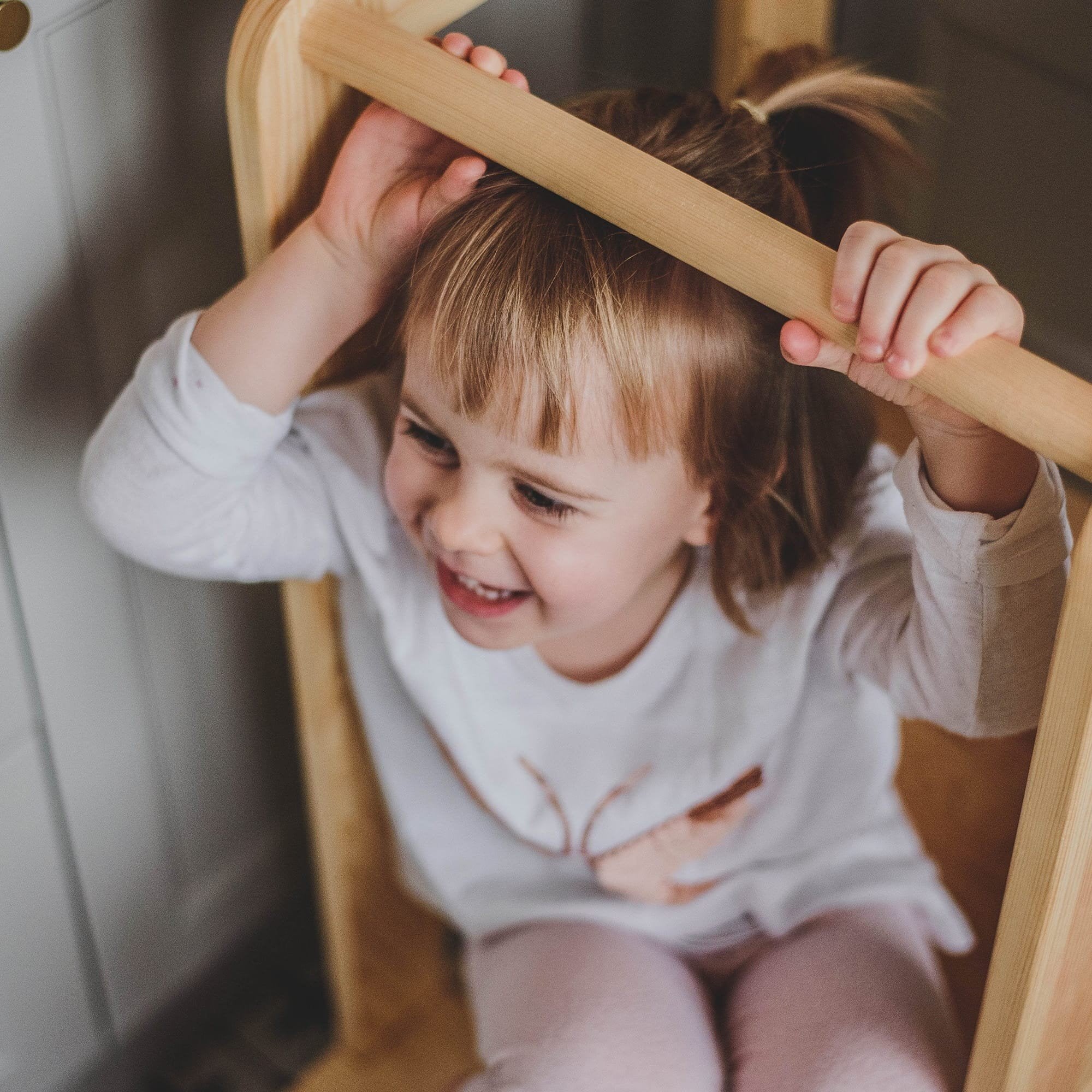 12. Happy child sitting on MeowBaby kitchen helper, holding onto the rail