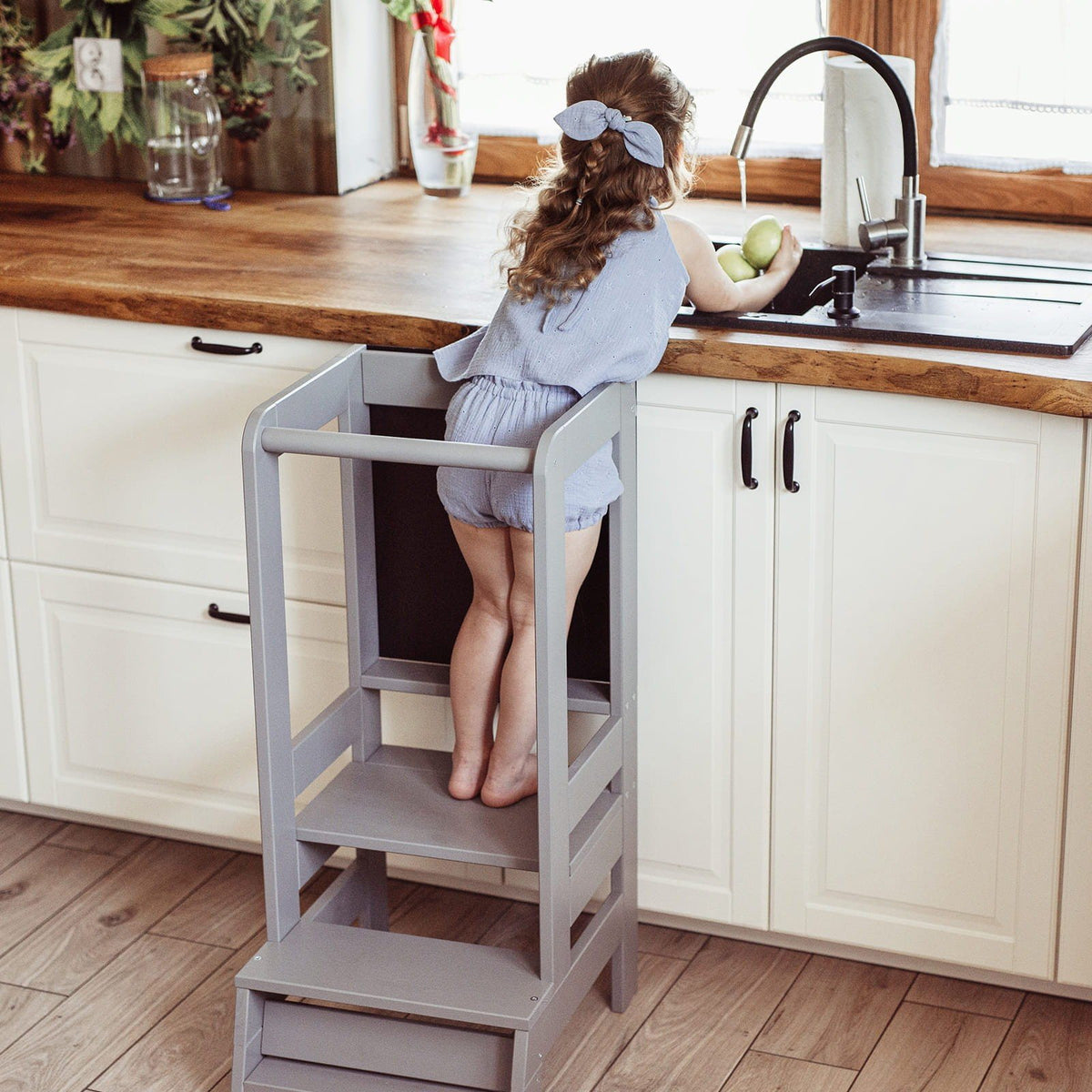 1. Girl reaching sink using dark grey MeowBaby kitchen helper in home kitchen