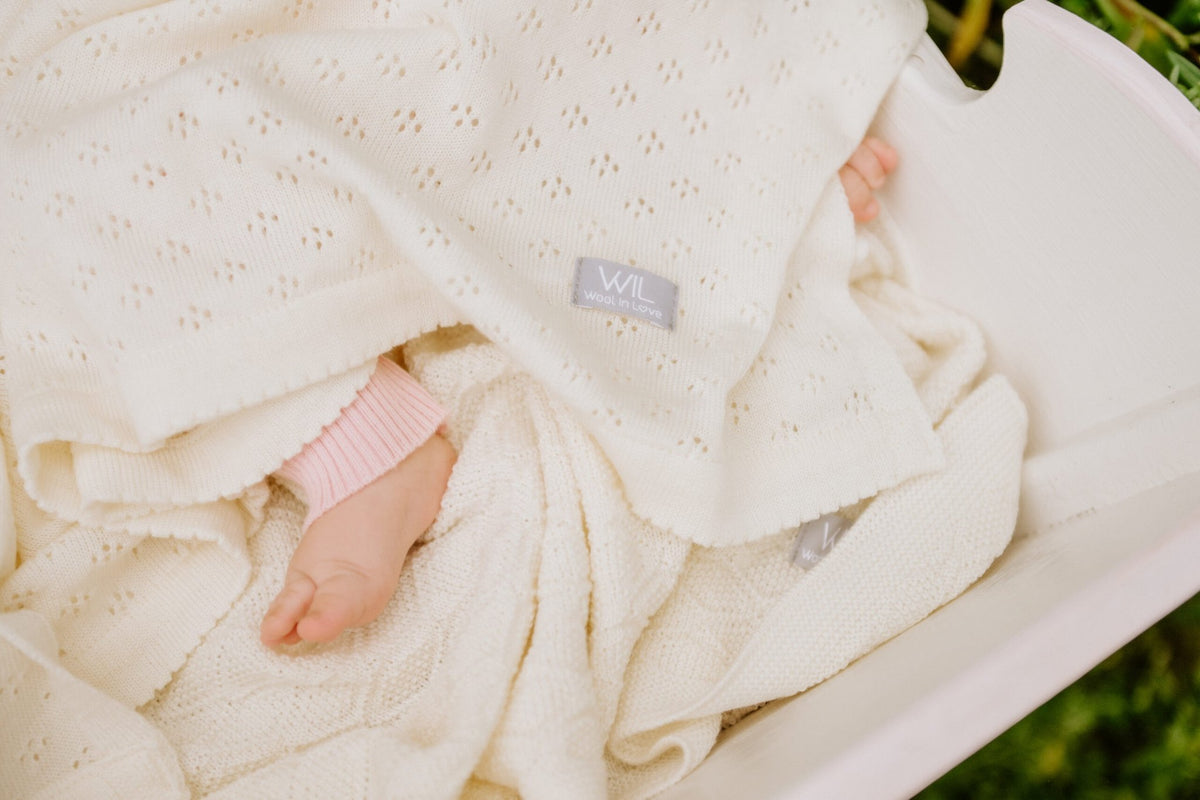 13. Close-up of cream merino wool blanket with floral pattern and baby feet