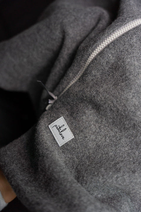 5. Close-up of Patulove logo on grey merino wool fabric with zipper detail
