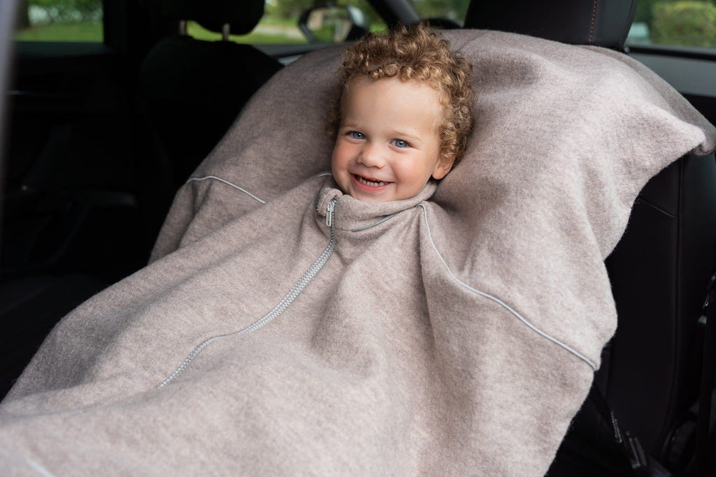 3. Smiling child in car seat wearing beige merino wool poncho with zipper