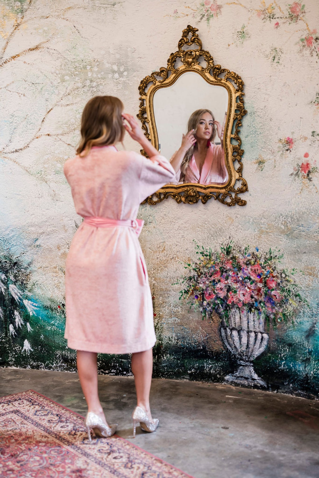 5. Back view of woman in pink bamboo terry robe with shawl collar adjusting hair in front of mirror